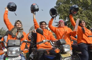 Women participants of Women on Wheels (WOW) raise their helmets at the start of a rally launching the Women on Wheels campaign in Lahore on January 10, 2016.